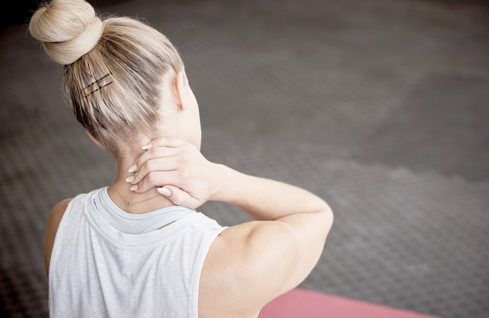 Frau mit Nackenschmerzen am Arbeitsplatz durch Bandscheibenvorfall