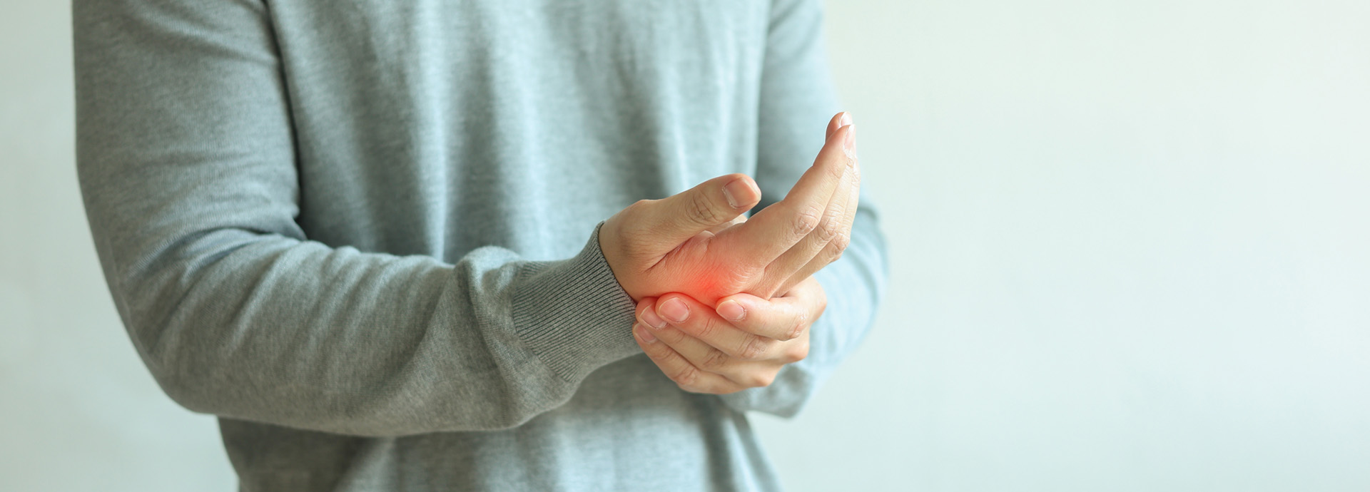 Person hält sich aufgrund von Schmerzen das Handgelenk