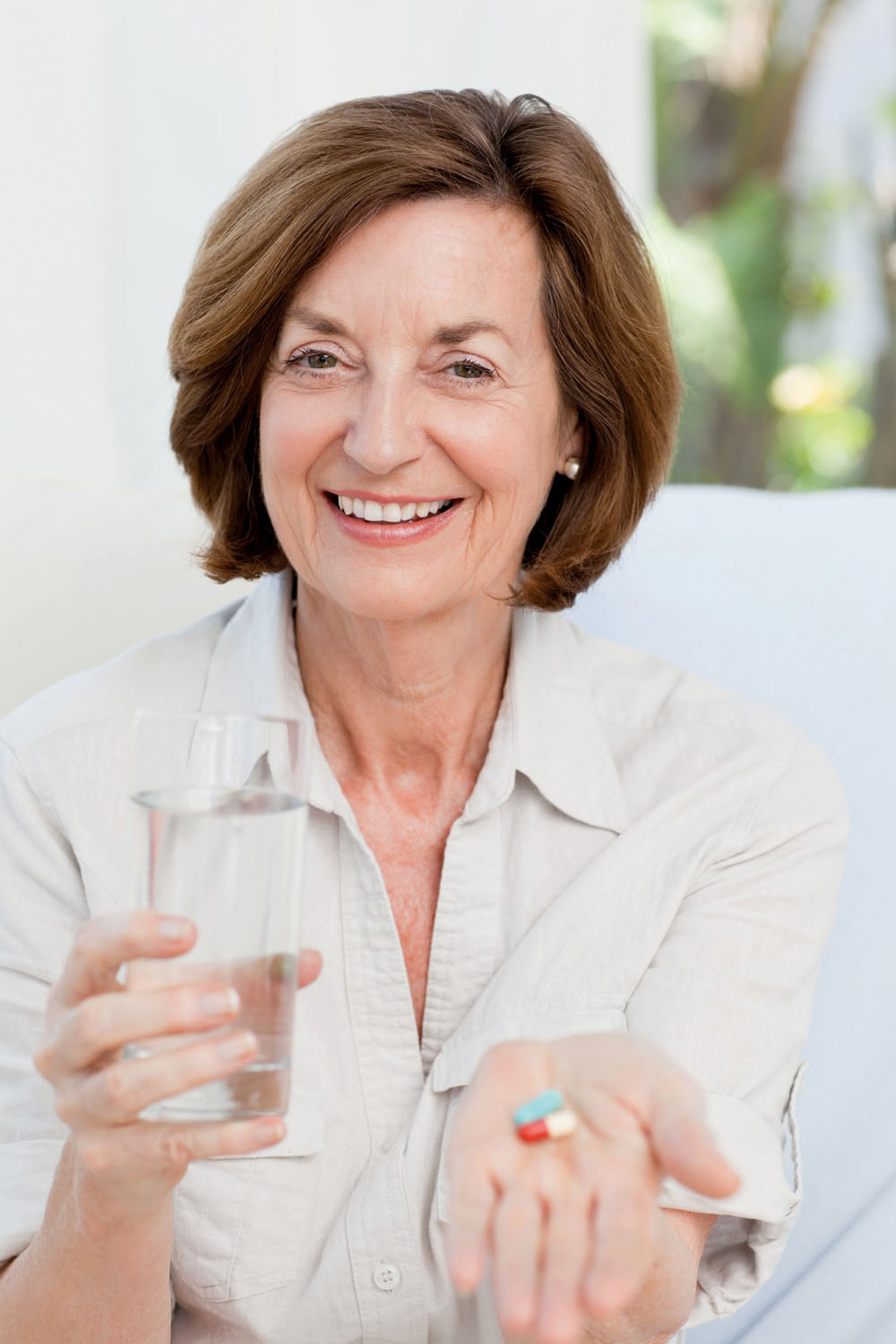 Frau hält Medikamente und Glas Wasser zur Behandlung von Herzinsuffizienz