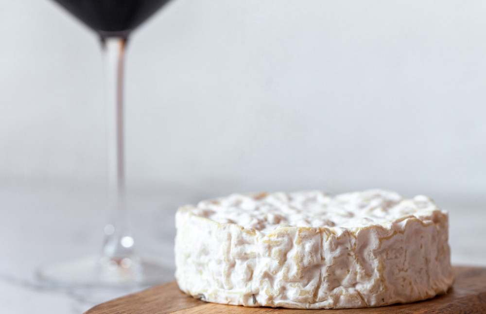 Weinglas und Käse als mögliche Auslöser für Kopfschmerzen dargestellt