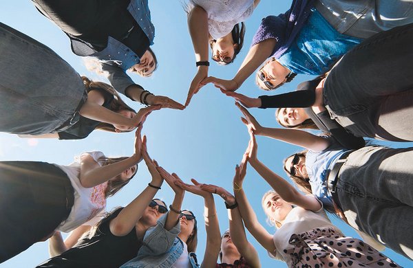 Menschen stehen im Kreis und bilden ein Herz mit den Händen