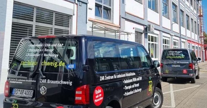 Schwarzer Transporter mit ZAR-Beschriftung, geparkt vor dem Gebäude, bietet Fahrdienst für Patient*innen an.
