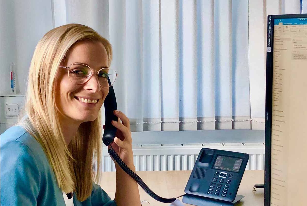 Empfangsmitarbeiterin telefoniert am Schreibtisch.