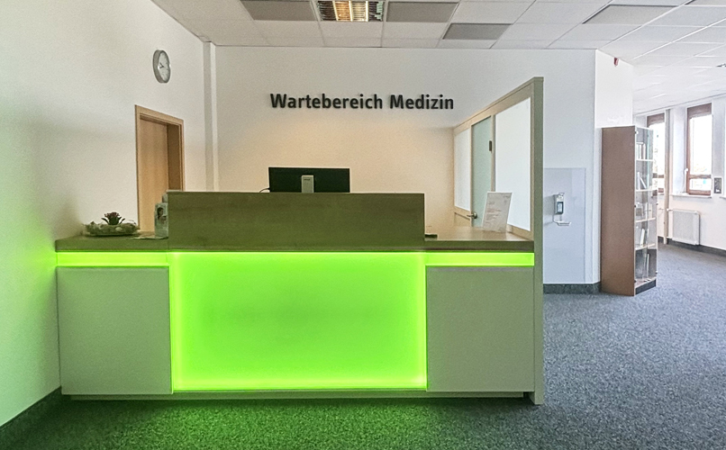 Empfangsbereich Medizin mit grün beleuchtetem Tresen im ZAR Augsburg.