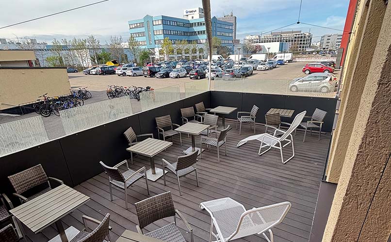 Sitzbereich auf der sonnigen Terrasse des ZAR Augsburg mit Blick auf Parkplatz