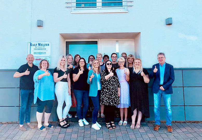 Foto des 12-köpfigen Teams Nanz medico Consult vor dem Gebäude in Vinningen.