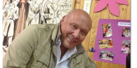 Ein Mann in Freizeitkleidung lächelt in einer geschmückten Umgebung.