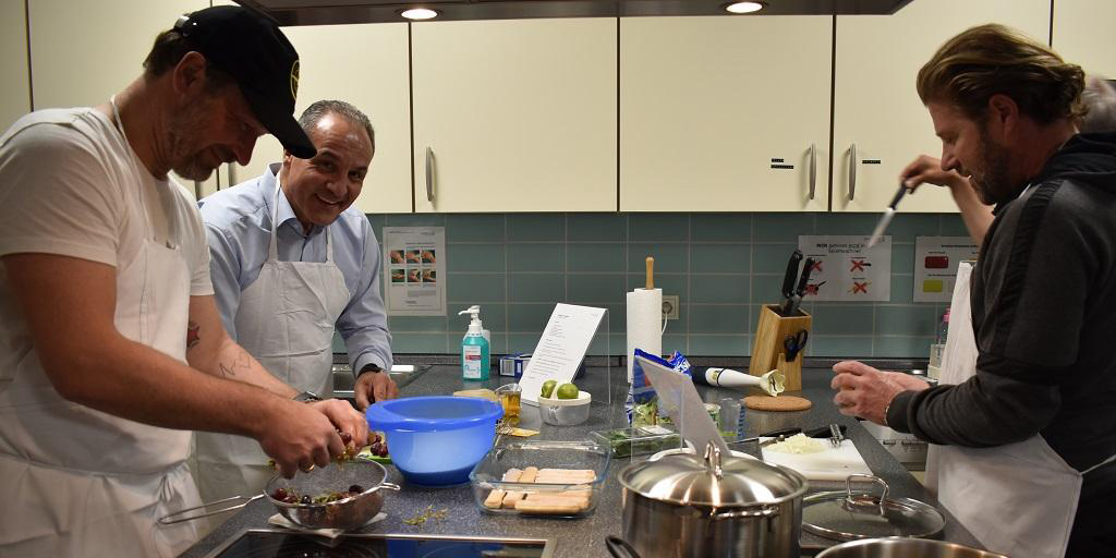 Drei Männer kochen gemeinsam in einer modernen Küche.